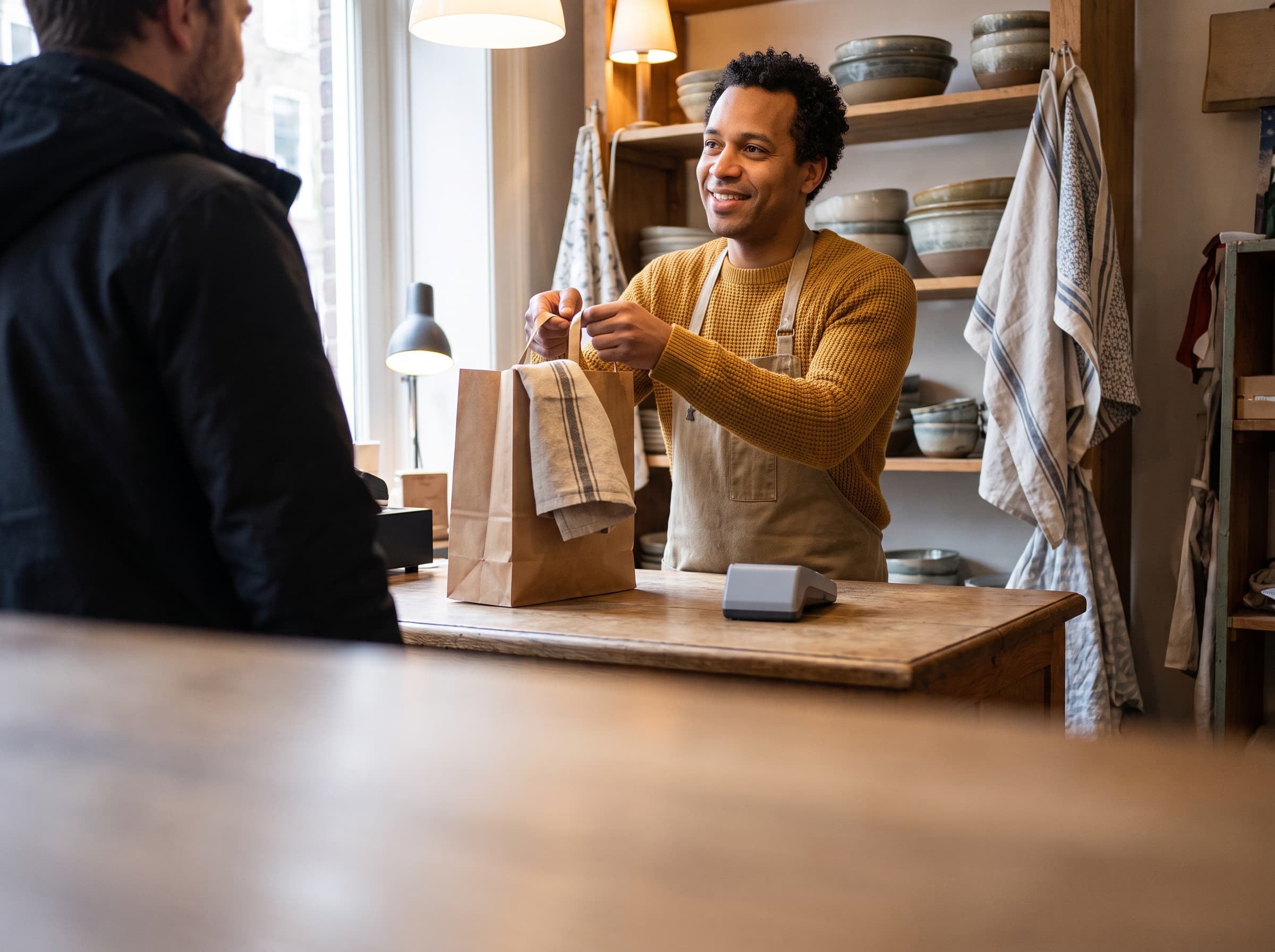 Shop assistant handing a customer a paper bag at the counter